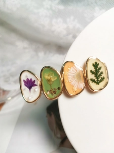 Détail d'une barrette en résine faite main avec fleurs séchées et cadre doré