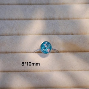 Detail eines handgefertigten Edelstahlrings mit 8x10mm getrockneter Blume in Harz