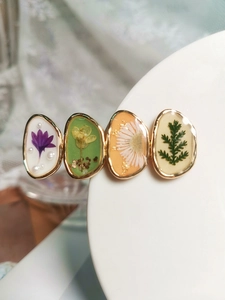 Détail d'une barrette en résine avec de vraies fleurs séchées et bordure dorée