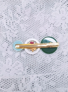 Détail de la pince à cheveux dorée avec breloques en résine, fleurs séchées et feuilles d'or