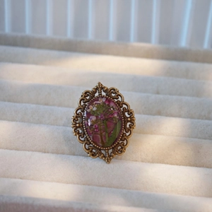Detail of vintage bronze ring featuring handmade resin-encased real dried flowers