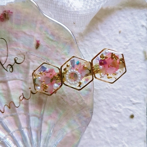 Handmade resin hair clip with pink dried petals, gold foil, and white pearls in gold frame