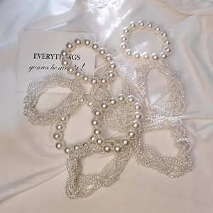 Elegant white pearl hair tie and crystal beaded bracelet set on white satin fabric