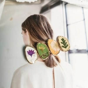 Barrette à fleurs avec spécimens botaniques réels et cadre doré sur photo de mode