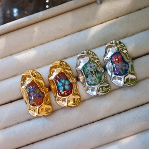 Close-up of handmade stainless steel rings with real dried flowers in resin inlay