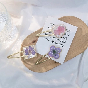 Macro detail of three handmade hair clips with dried flowers and pearls in resin