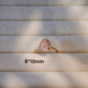 Nahaufnahme des handgefertigten Rings mit getrockneten Blumen und Goldfolien-Details