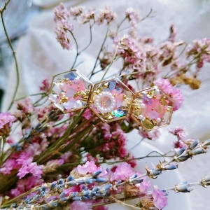 Close-up of handmade resin hair clip with pink dried flowers, gold leaf and pearls
