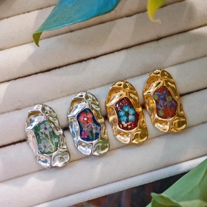 Handmade pressed flower rings with gold and silver lava frames on beige velvet tray