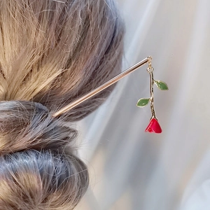 Elegant gold rose hair stick with red enamel flower bud worn in a brown hair bun