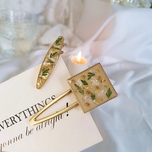 Handmade resin hair clips set with dried green leaves and gold foil on white cards