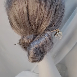 Detail eines goldenen Haarstabs mit einem durchsichtigen Erdbeer-Anhänger für Sommertage