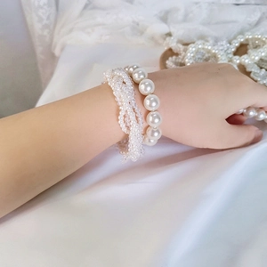 Detailed shot of elegant crystal pearl hair ties and beaded bracelets on hand