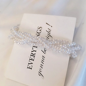 Macro shot of elegant white pearl and crystal beaded hair tie on a card