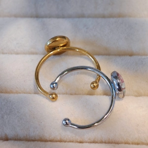 Detail von verstellbaren C-förmigen Ringen mit runden Tablett-Designs in Gold und Silber