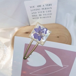 Detail of square hair clip with purple dried flowers and pearls on wooden base