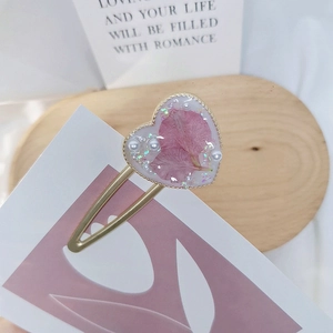 Macro shot of heart-shaped hair clip with real pink dried flowers and white pearls