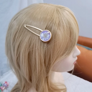 Detailed close-up of a golden BB hair clip featuring purple dried flowers and pearls
