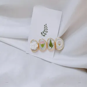 Vue détaillée d'une barrette florale avec roses blanches, tulipes et perles sur or