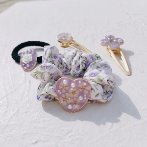 Detailed set of purple floral hair accessories including resin flower clips and scrunchie