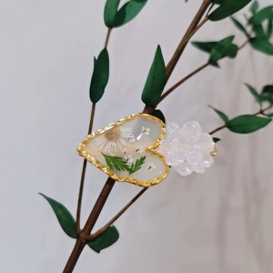 Floral resin hair clip with white dried flowers and green leaves in golden frame