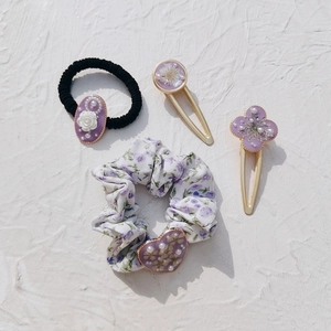 Detailed shot of purple crystal hair accessories including scrunchie and floral hairpins