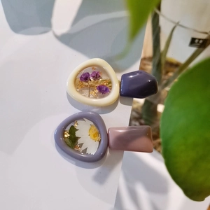 Dettaglio di fermagli in resina con veri fiori secchi viola e decorazioni in foglia d'oro