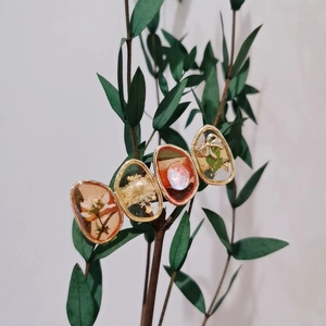 Détail d'une pince à cheveux artisanale en résine avec fleurs séchées et feuilles vertes