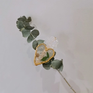 Detail of heart-shaped resin hair clip with dried white daisies and gold wave edges
