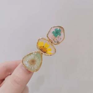 Handmade resin hair clip featuring colorful dried flowers in gold metal frames