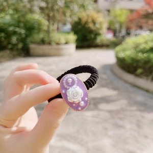 Close-up of a purple vintage floral scrunchie with white rose relief and pearls detail