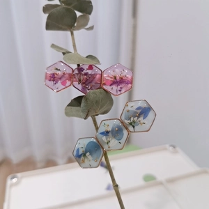 Handgefertigte hexagonale Harz-Anhänger mit Trockenblumen und Goldfolie im Detail