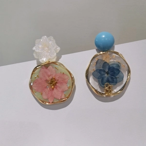 Détails de boucles d'oreilles en résine fait main avec fleurs séchées et feuilles d'or