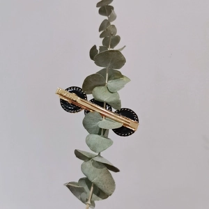 Detail einer goldenen Haarspange mit schwarzen Akzenten und Korea-Gravur auf Metall