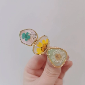 Detailed close-up of handmade resin hair clip with embedded real dried flowers and gold frame