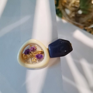 Dettaglio ravvicinato di fermaglio in resina fatto a mano con fiori secchi e foglie d'oro