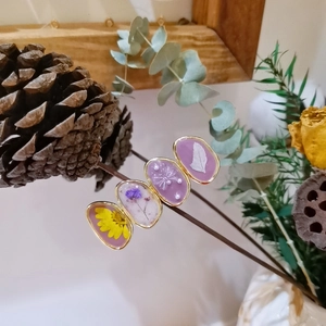 Detail showing resin hair clips with real dried flowers and gold metal framing