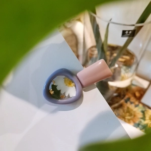 Dettaglio del fermaglio per capelli in resina viola con margherita vera e lamina d'oro