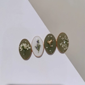 Détail de la pince à cheveux artisanale avec fleurs séchées et pendentif coeur doré
