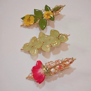 Detail view of three handmade resin hair clips with real dried flowers and gold foil accents