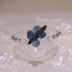 Detailed macro view of handmade blue hydrangea bead bracelet with gold leaf and glass beads