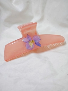 Macro detail of handmade hair claw clip with purple dried flower and golden bead accent