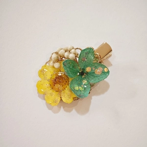 Handmade resin sunflower hair clip with green petals and golden metal duckbill base