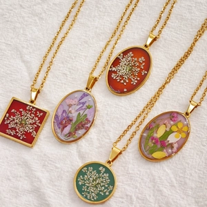 Detailed view of handmade pressed dried flower pendants in gold stainless steel frames