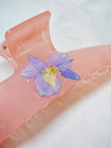 Macro detail of handmade hair claw with real purple dried flowers in pink resin