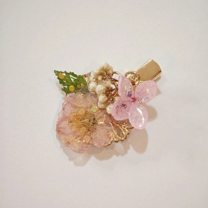 Handmade dried flower hair clip with pink petals and gold glitter on an alloy base