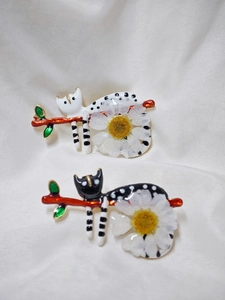Gros plan de broches chat faites main avec marguerites blanches sur branche et détails fins
