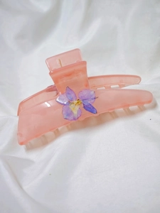 Detail of pink resin hair claw clip with purple dried flower and floral decoration