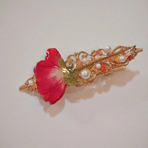 Handmade hair clip with dried red rose petal, pearls and gold base on white background