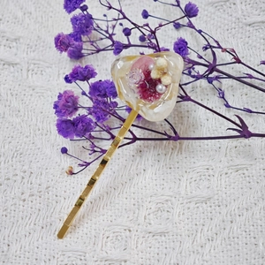 Détail d'une barrette dorée avec résine en forme de cœur et fleurs séchées incrustées